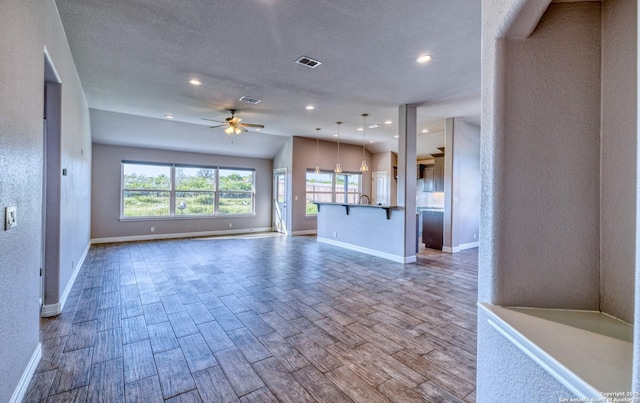 13 Hope, Uvalde, TX 78801 - unfurnished living room with a ceiling fan, plenty of natural light, wood finished floors, recessed lighting, and a textured wall