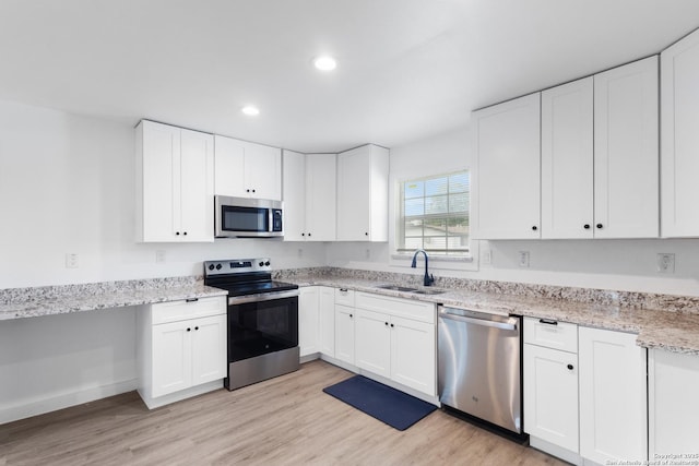 502 E Palfrey, San Antonio, TX 78223 - kitchen with appliances with stainless steel finishes, recessed lighting, light stone counters, light wood-type flooring, and white cabinetry