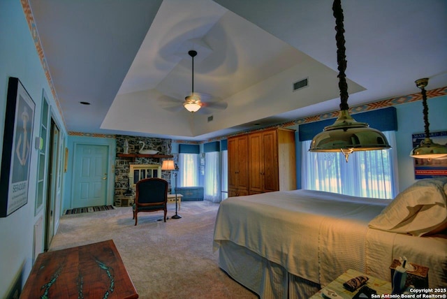 142 Four Bears Trl, Kerrville, TX 78028 - bedroom with a tray ceiling, light carpet, and a stone fireplace