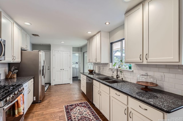 547 Patricia, San Antonio, TX 78216 - kitchen featuring stainless steel appliances, light wood-type flooring, tasteful backsplash, washer / dryer, and dark stone countertops