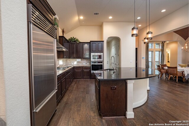 12 Denbury Gln, San Antonio, TX 78257 - kitchen featuring built in appliances, arched walkways, dark wood finished floors, dark brown cabinetry, and lofted ceiling