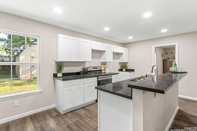 8810 Flint Vly, San Antonio, TX 78227 - kitchen with dark wood finished floors, stainless steel electric range oven, white cabinets, recessed lighting, and dark stone countertops