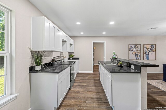 8810 Flint Vly, San Antonio, TX 78227 - kitchen featuring stainless steel range with electric stovetop, dark wood-style floors, recessed lighting, a center island with sink, and white cabinets