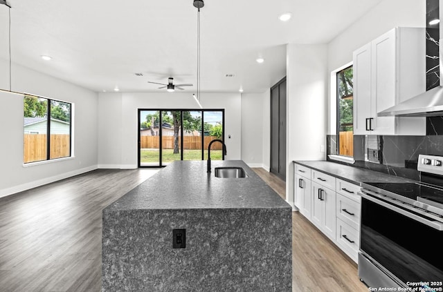 302 Bank, San Antonio, TX 78204 - kitchen with stainless steel electric stove, wall chimney range hood, light wood-style flooring, ceiling fan, and recessed lighting