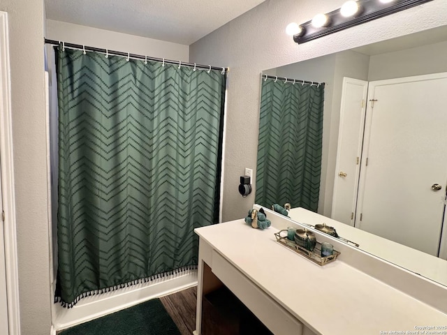 6914 Sandy Pt, San Antonio, TX 78244 - bathroom with vanity, a textured wall, curtained shower, and wood finished floors