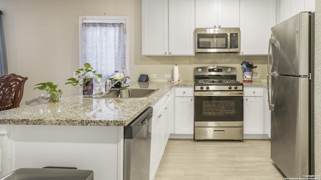 7207 Rosada Way, San Antonio, TX 78218 - kitchen featuring appliances with stainless steel finishes, white cabinetry, a peninsula, and light stone countertops