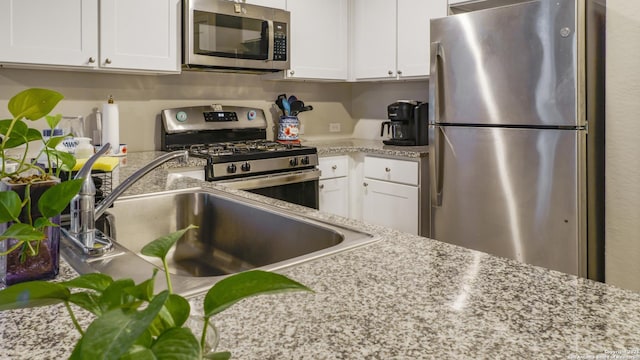 7207 Rosada Way, San Antonio, TX 78218 - kitchen featuring appliances with stainless steel finishes, white cabinetry, and light stone counters