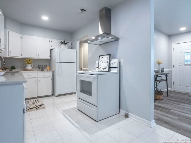131 Hartford, San Antonio, TX 78223 - kitchen with white appliances, wall chimney exhaust hood, light countertops, white cabinets, and recessed lighting
