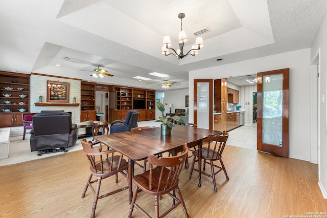 3523 Red Oak, San Antonio, TX 78230 - dining area featuring a ceiling fan, a raised ceiling, a fireplace, light wood-type flooring, and a textured ceiling