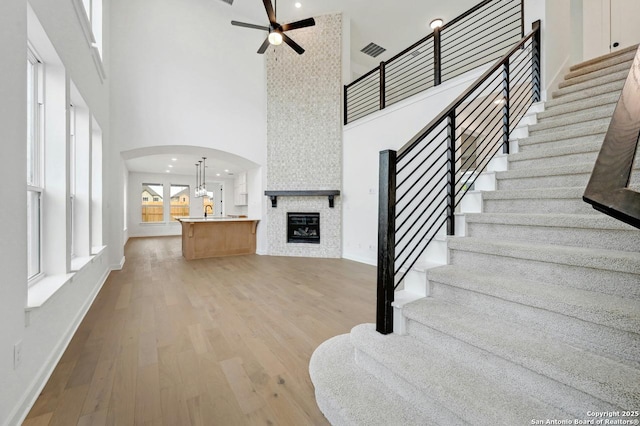 233 Alpine, New Braunfels, TX 78130 - stairway featuring a high ceiling, a ceiling fan, a fireplace, arched walkways, and wood finished floors