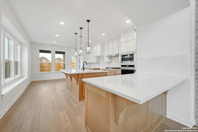 233 Alpine, New Braunfels, TX 78130 - kitchen featuring stainless steel appliances, a breakfast bar, light wood finished floors, a kitchen island with sink, and recessed lighting