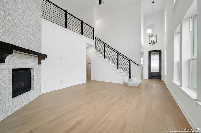 233 Alpine, New Braunfels, TX 78130 - unfurnished living room with a high ceiling, wood finished floors, a chandelier, a brick fireplace, and stairs