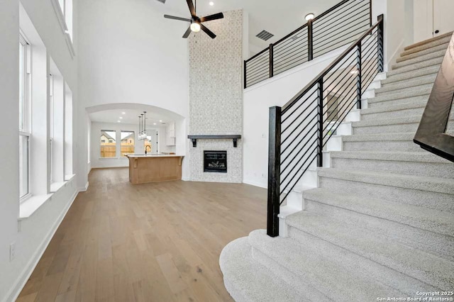 233 Alpine, New Braunfels, TX 78130 - stairway featuring a high ceiling, ceiling fan, a fireplace, arched walkways, and wood finished floors