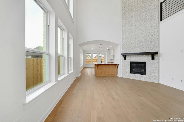 233 Alpine, New Braunfels, TX 78130 - unfurnished living room featuring a high ceiling, light wood finished floors, a fireplace, and arched walkways