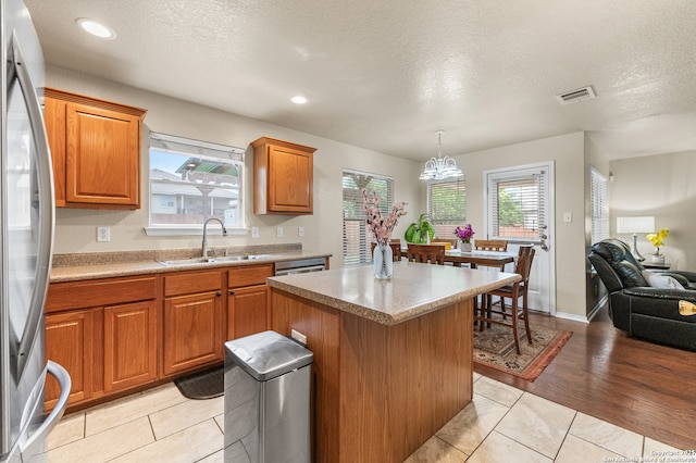 10223 Cactus Vly, San Antonio, TX 78254 - kitchen with freestanding refrigerator, brown cabinetry, a center island, a textured ceiling, and plenty of natural light