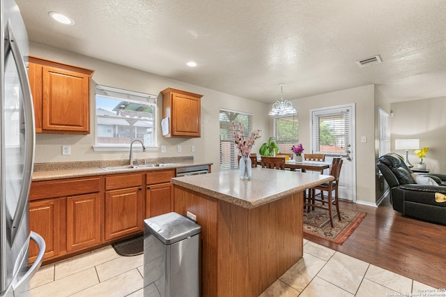 10223 Cactus Vly, San Antonio, TX 78254 - kitchen featuring freestanding refrigerator, brown cabinetry, a kitchen island, a textured ceiling, and open floor plan