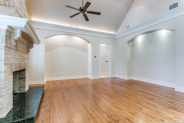 600 Thelma, Olmos Park, TX 78212 - unfurnished living room with ceiling fan, vaulted ceiling, arched walkways, a brick fireplace, and wood finished floors