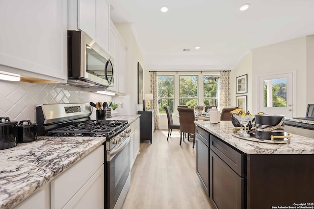 1587 Vista View Dr, Pleasanton, TX 78064 - kitchen featuring appliances with stainless steel finishes, decorative backsplash, white cabinets, light wood-style floors, and light stone countertops