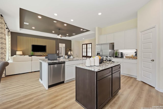 1587 Vista View Dr, Pleasanton, TX 78064 - kitchen with appliances with stainless steel finishes, an island with sink, a tray ceiling, open floor plan, and light wood-style floors