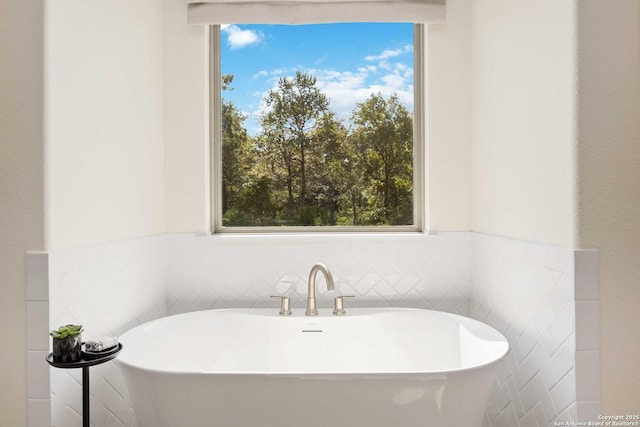 1587 Vista View Dr, Pleasanton, TX 78064 - full bath featuring a freestanding bath, tile walls, plenty of natural light, and a wainscoted wall