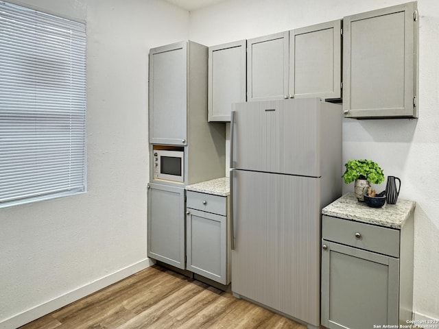 102 Aganier Ave, San Antonio, TX 78212 - kitchen featuring white appliances, gray cabinets, light wood-style floors, and light stone countertops