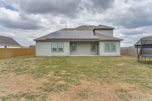 29125 Rock Cyn, Bulverde, TX 78163 - back of house featuring a trampoline, a fenced backyard, solar panels, and roof with shingles
