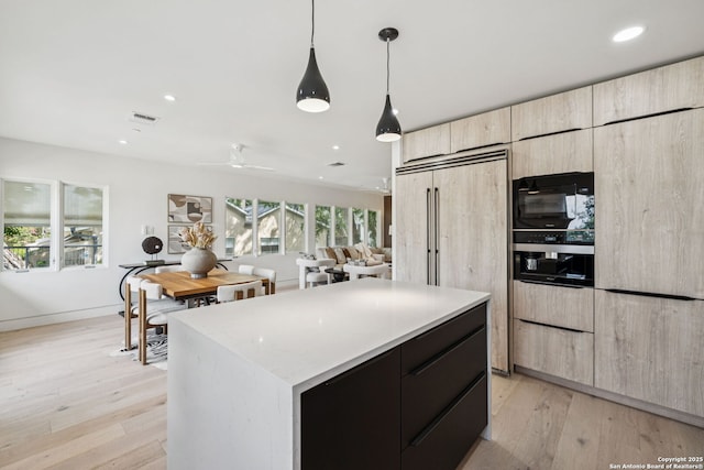 305 Joliet Unit D, San Antonio, TX 78209 - kitchen with modern cabinets, light brown cabinetry, a kitchen island, black microwave, and light wood-type flooring