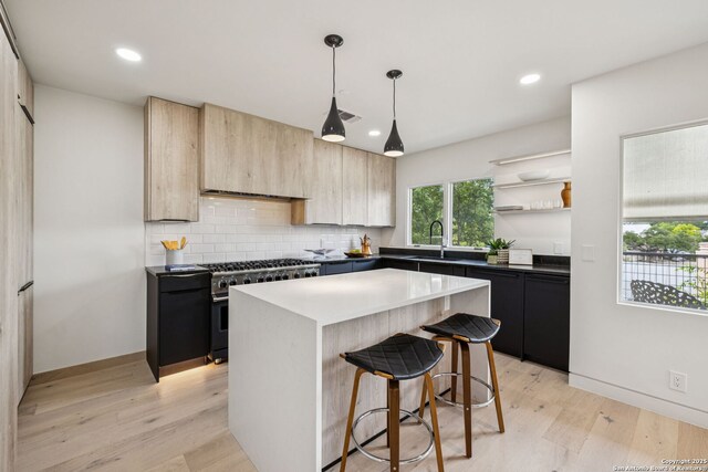 305 Joliet Unit D, San Antonio, TX 78209 - kitchen featuring high end stainless steel range oven, light brown cabinetry, light wood-type flooring, backsplash, and a center island