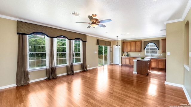 8023 Jalane Oaks, San Antonio, TX 78255 - kitchen with brown cabinets, a center island, a ceiling fan, light countertops, and ornamental molding