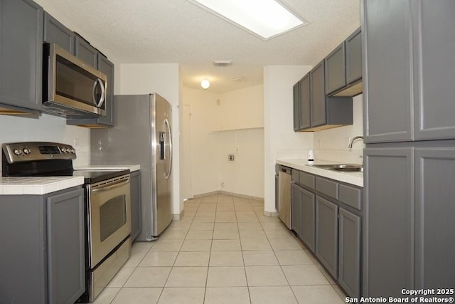 5615 Camry Spgs, San Antonio, TX 78251 - kitchen featuring appliances with stainless steel finishes, gray cabinetry, and light tile patterned flooring
