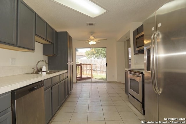 5615 Camry Spgs, San Antonio, TX 78251 - kitchen featuring appliances with stainless steel finishes, tile countertops, light tile patterned floors, and a ceiling fan