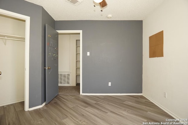 5615 Camry Spgs, San Antonio, TX 78251 - unfurnished bedroom featuring wood finished floors, a closet, a textured ceiling, a walk in closet, and ceiling fan