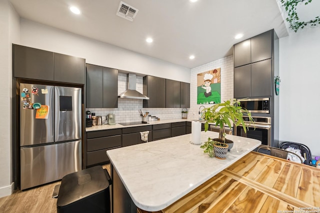 818 Martin Luther King, San Antonio, TX 78203 - kitchen featuring appliances with stainless steel finishes, wall chimney range hood, light wood finished floors, backsplash, and recessed lighting