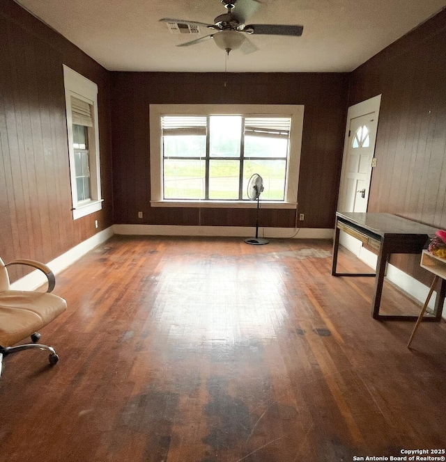335 E San Antonio St, Marion, TX 78124 - unfurnished living room with wood finished floors, wood walls, and a ceiling fan