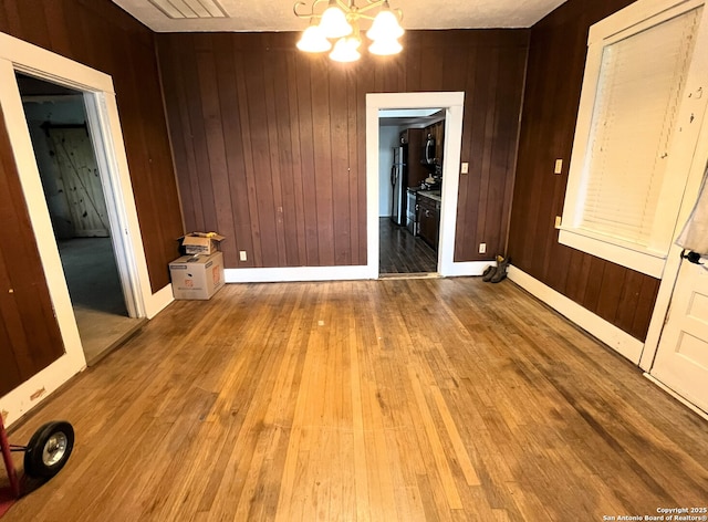 335 E San Antonio St, Marion, TX 78124 - unfurnished dining area featuring a chandelier, hardwood / wood-style floors, and wood walls