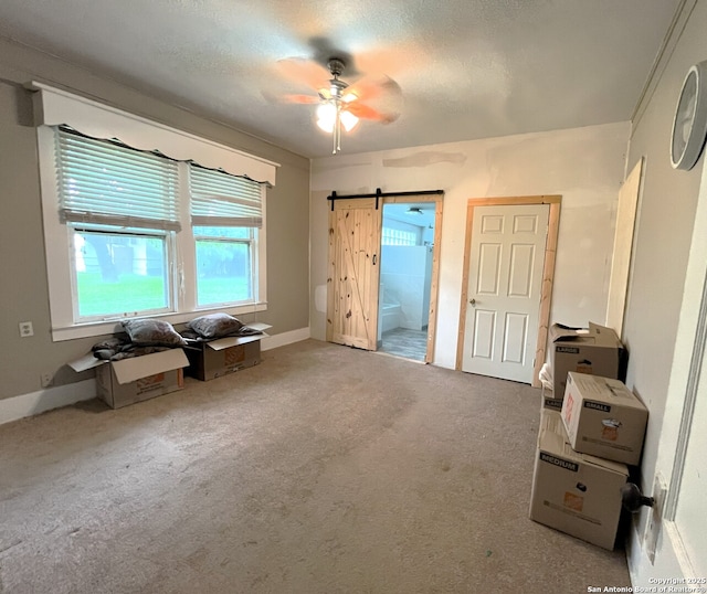 335 E San Antonio St, Marion, TX 78124 - unfurnished bedroom featuring carpet flooring, ensuite bathroom, ceiling fan, and a barn door