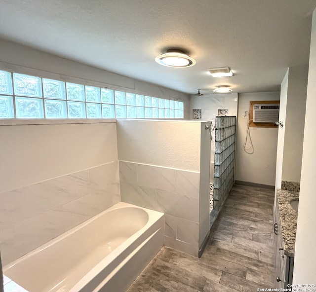 335 E San Antonio St, Marion, TX 78124 - full bathroom with vanity, a garden tub, a wall unit AC, walk in shower, and wood finished floors