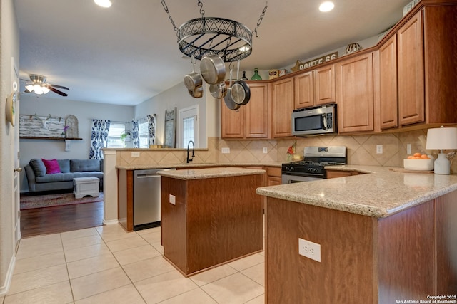 1154 Kite, New Braunfels, TX 78130 - kitchen featuring appliances with stainless steel finishes, a peninsula, light tile patterned floors, a center island, and light stone countertops