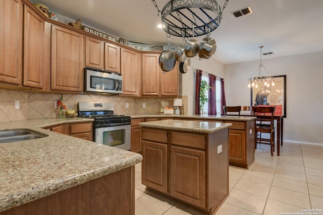 1154 Kite, New Braunfels, TX 78130 - kitchen featuring appliances with stainless steel finishes, a peninsula, light tile patterned flooring, and decorative backsplash