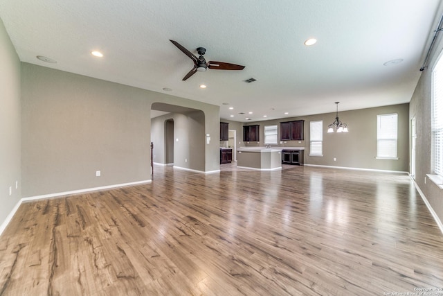129 Sandy Shl, Boerne, TX 78006 - unfurnished living room featuring ceiling fan, arched walkways, light wood-style floors, and recessed lighting