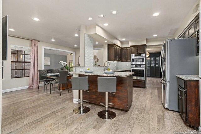 2915 Quail Oak, San Antonio, TX 78232 - kitchen with dark brown cabinets, stainless steel appliances, light wood-style floors, backsplash, and a peninsula