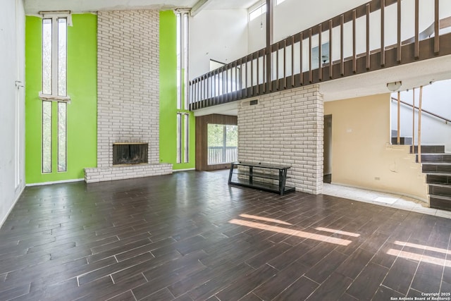 6231 Little Fawn, San Antonio, TX 78238 - unfurnished living room featuring a fireplace, a towering ceiling, stairs, and wood finished floors