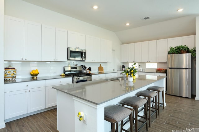 5798 Luciano Trl, Seguin, TX 78155 - kitchen featuring stainless steel appliances, wood finish floors, a breakfast bar, tasteful backsplash, and a center island with sink