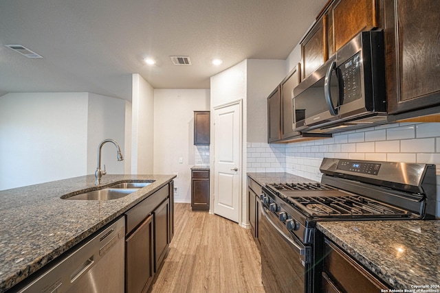7119 Magnolia Blf, San Antonio, TX 78218 - kitchen featuring stainless steel appliances, light wood-style floors, dark stone countertops, tasteful backsplash, and recessed lighting