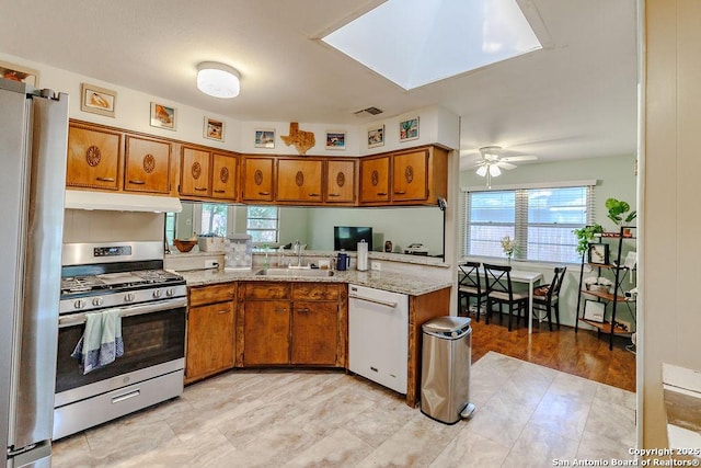 5634 Charlie Chan, San Antonio, TX 78240 - kitchen with appliances with stainless steel finishes, under cabinet range hood, brown cabinets, a ceiling fan, and a peninsula