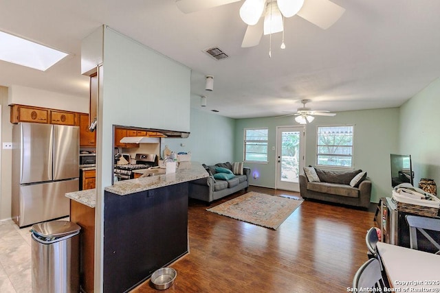 5634 Charlie Chan, San Antonio, TX 78240 - kitchen with appliances with stainless steel finishes, brown cabinets, a ceiling fan, a skylight, and a peninsula