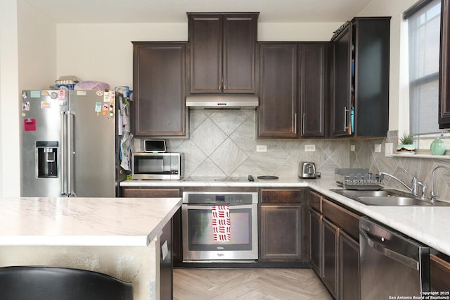 561 Dusty Emerald, Universal City, TX 78148 - kitchen featuring stainless steel appliances, under cabinet range hood, light countertops, tasteful backsplash, and dark brown cabinets