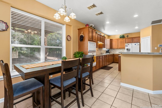 2611 Menard, San Antonio, TX 78251 - kitchen featuring white appliances, a chandelier, light tile patterned floors, light countertops, and pendant lighting