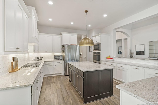 9032 Raven Pointe, San Antonio, TX 78255 - kitchen with stainless steel appliances, backsplash, white cabinetry, recessed lighting, and arched walkways