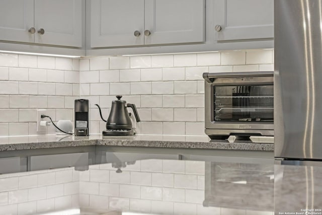 9032 Raven Pointe, San Antonio, TX 78255 - kitchen view of tasteful backsplash, freestanding refrigerator, and light stone countertops